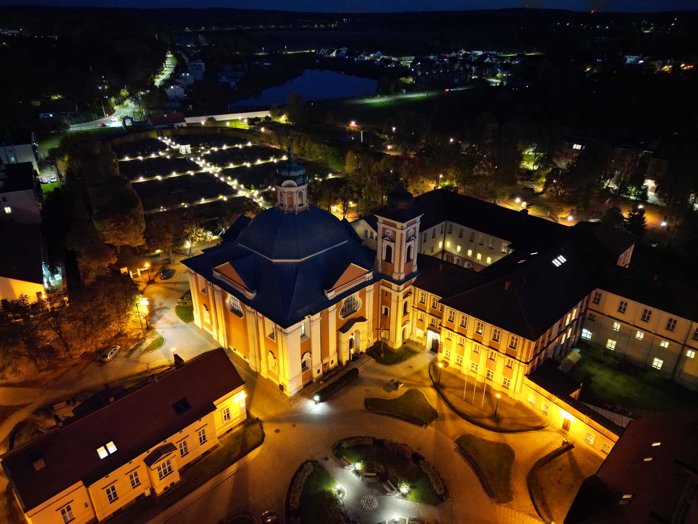 Iluminowany klasztor w Owińskach nocą z lotu ptaka