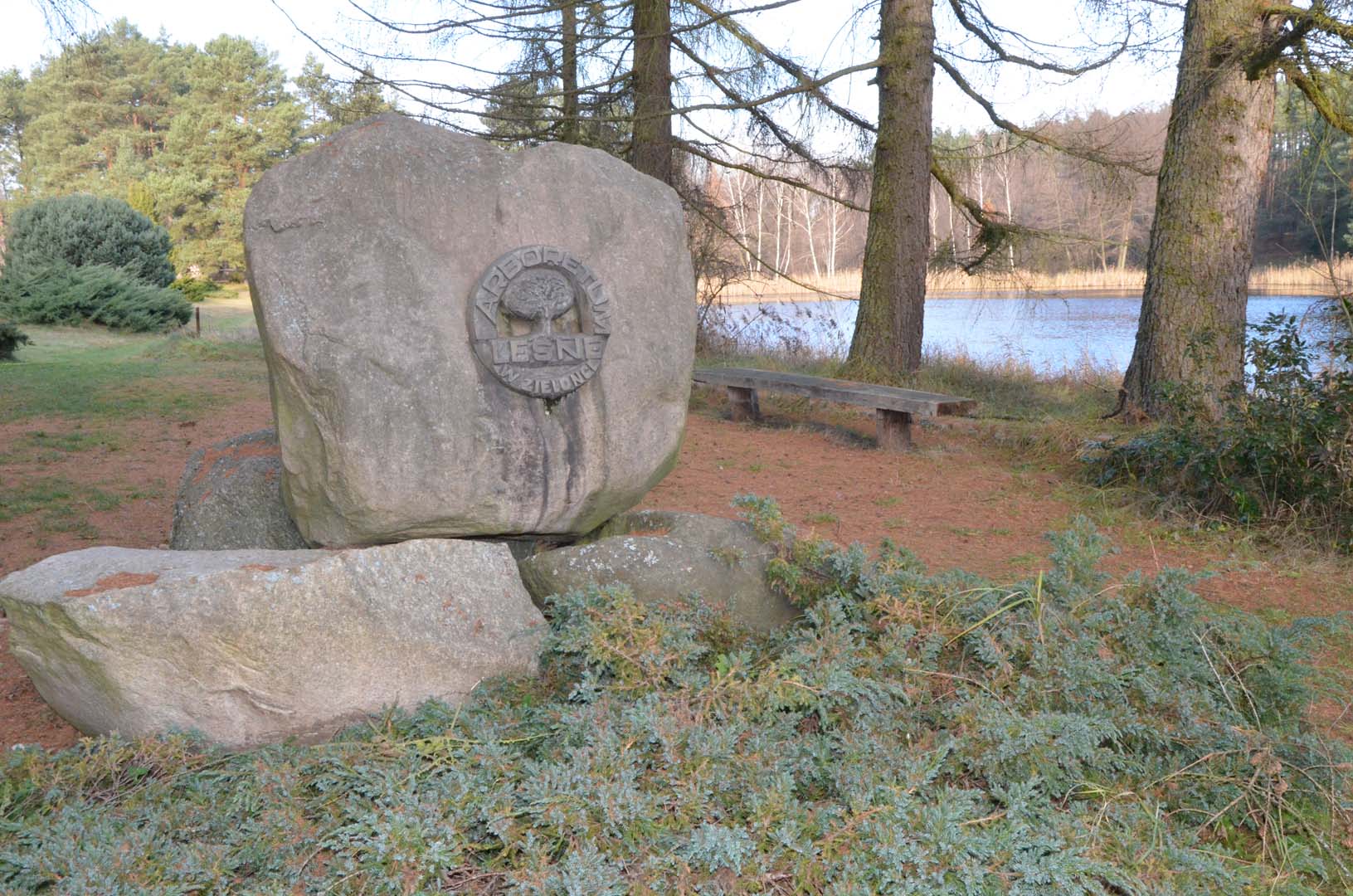 Głaz z godłem Arboretum Leśnego w Zielonce nad stawem