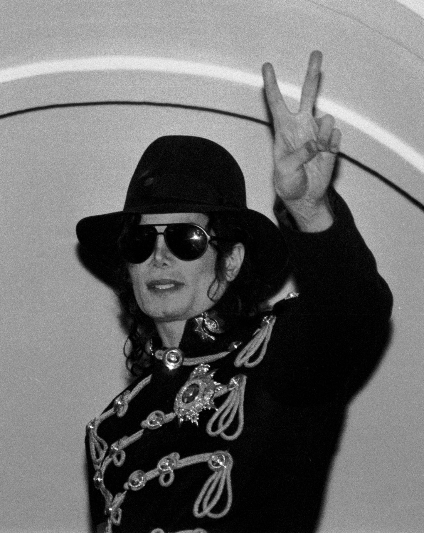 Michael Jackson w kapeluszu i okularach pokazuje znak wiktorii